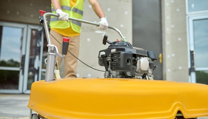 Cropped photo of a worker cleaning the outdoor floor tiles with a street sweeping machine